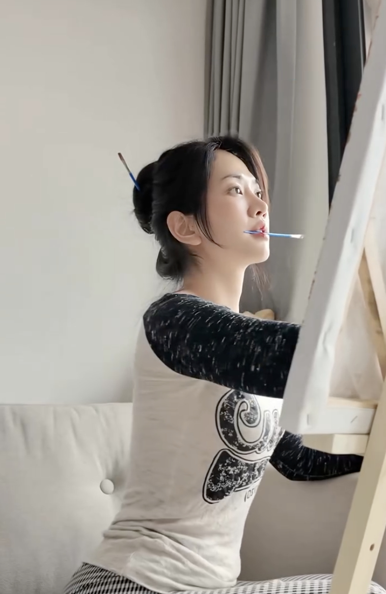 Cả TikTok hóa Lê Bống: Miệng ngậm cọ, tay tô màu, mắt nhìn xa xăm- Ảnh 1. Hình ảnh Lê Bống ngậm cọ vẽ tranh